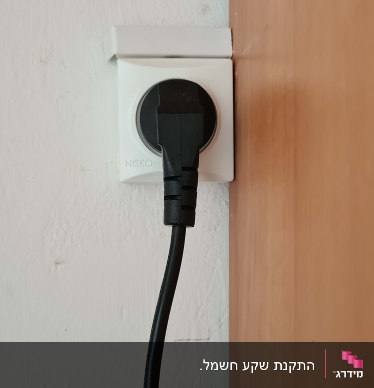 תקע חשמלי שחור בשקע קיר לבן